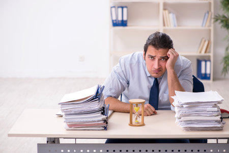 Young male employee in time management conceptの写真素材