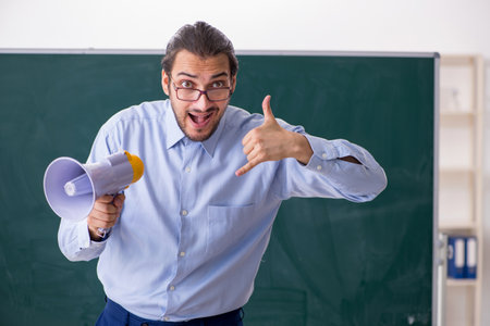 Young male teacher in the classroom holding megaphoneの写真素材