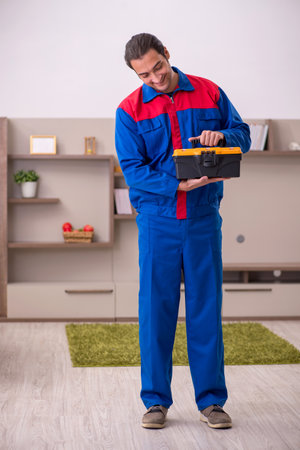Young male contractor repairing furniture indoorsの写真素材
