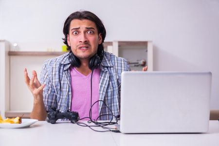 Young male student playing computer games at homeの写真素材