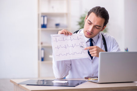 Young male doctor looking electrocardiogram in the clinicの写真素材