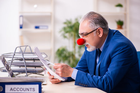 Old businessman clown working in the officeの写真素材