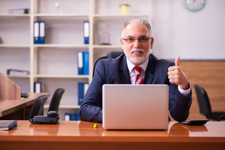 Old male employee sitting in the officeの写真素材