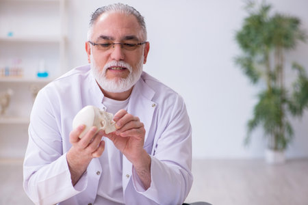 Old male anatomy teacher demonstrating human skeleton