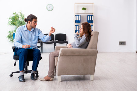 Pregnant woman visiting young male psychologistの写真素材
