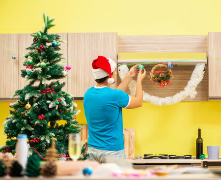 Young man celebrating Christmas in kitchenの写真素材