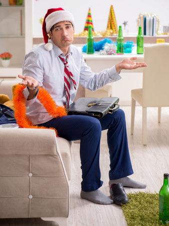 Young handsome employee celebrating Christmas at workplaceの写真素材