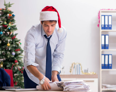 Young handsome employee celebrating Christmas at workplaceの写真素材