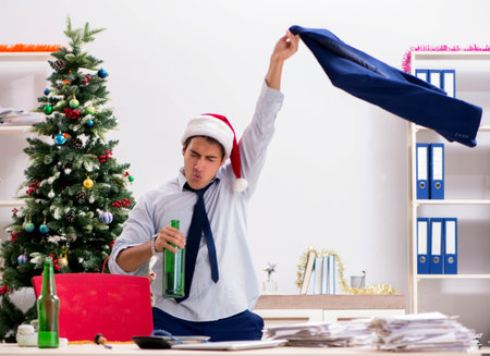 Young handsome employee celebrating Christmas at workplaceの写真素材