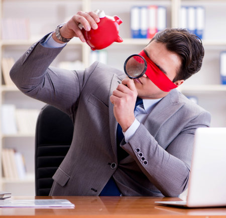 Blindfold businessman sitting at desk in officeの写真素材