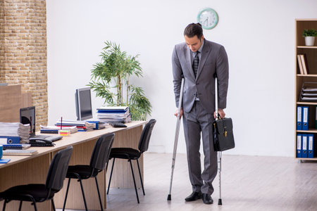 Young leg injured male employee working in the officeの写真素材