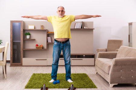 Aged man doing sport exercises at homeの写真素材