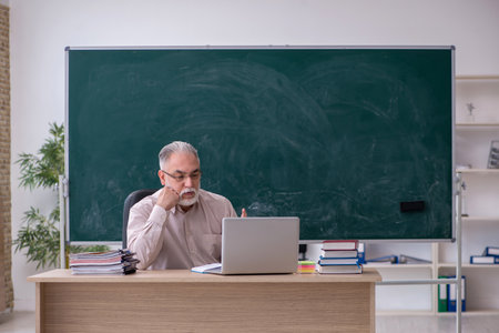 Old male teacher sitting in the classroomの写真素材