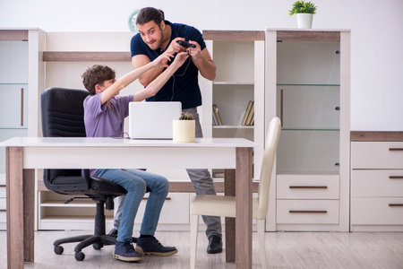 Young father and schoolboy playing computer games at homeの写真素材