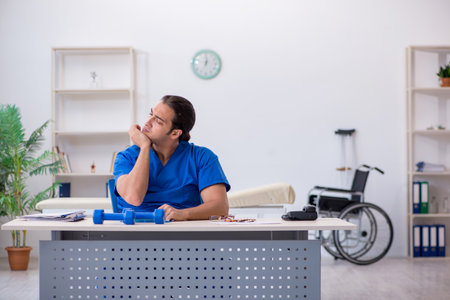 Young male doctor physiotherapist doing sport exercisesの写真素材