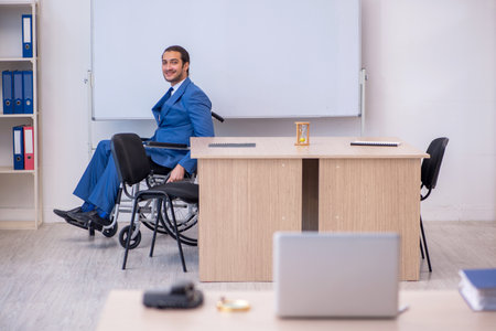 Young male employee in wheel-chair working in the officeの写真素材