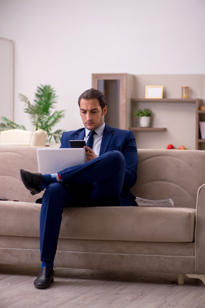Young male employee working from home in pandemic conceptの写真素材