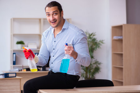 Young male employee cleaning office during pandemicの写真素材