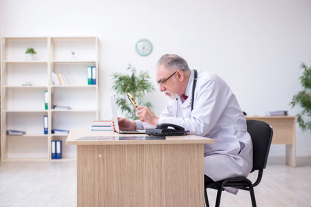 Old male doctor working in the clinicの写真素材