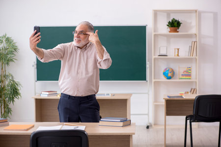 Old male teacher in front of blackboardの写真素材