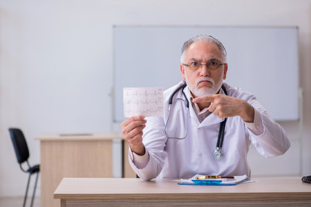 Old male doctor cardiologist working in the clinicの写真素材