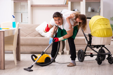 Young male contractor cleaning the house with his small daughterの写真素材