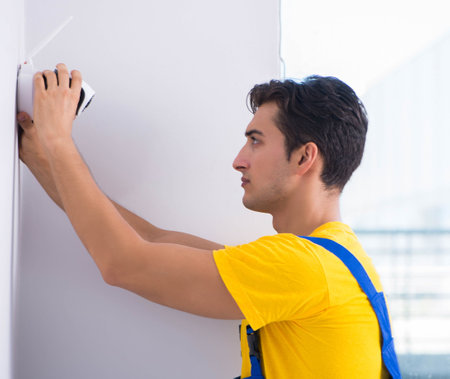 Contractor installing surveillance CCTV cameras in officeの写真素材