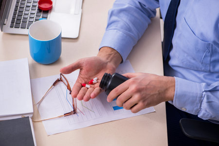 Sick male employee suffering at workplaceの写真素材
