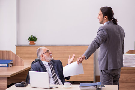 Old boss and young male assistant in the officeの写真素材