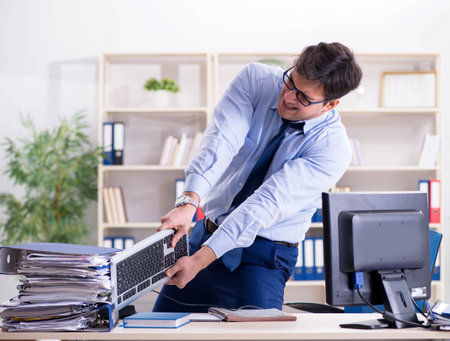 Angry businessman frustrated with too much workの写真素材