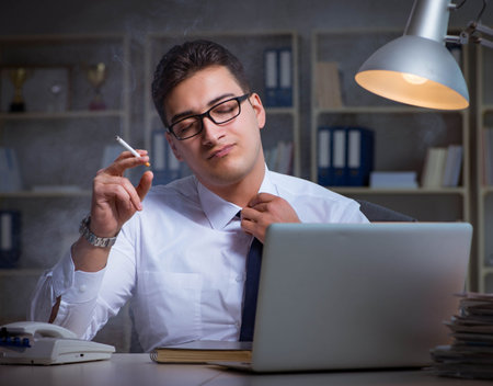 Businessman under stress smoking in officeの写真素材