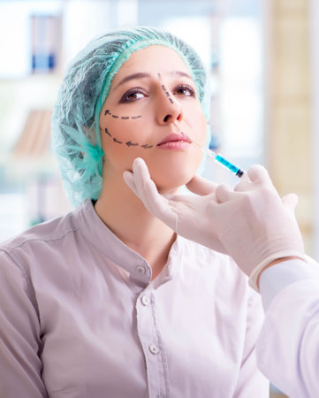 Plastic surgeon preparing for operation on woman faceの写真素材