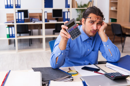 Young male bookkeper in budget planning conceptの写真素材