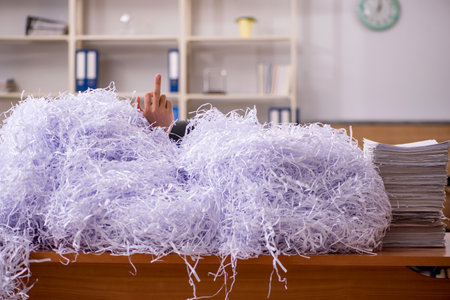 Young male employee and a lot of cut papers in the office