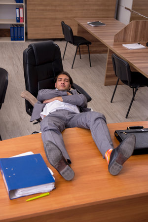 Young male employee sleeping at workplaceの写真素材