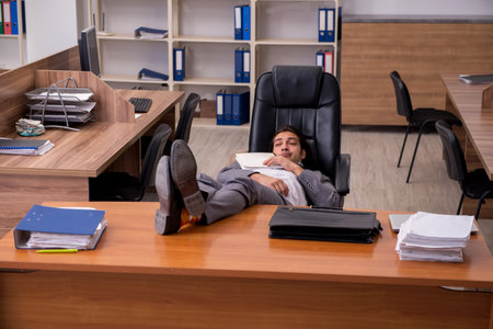 Young male employee sleeping at workplaceの写真素材