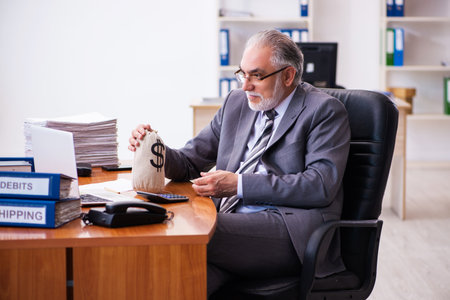 Old male businessman employee holding moneybag in the officeの写真素材