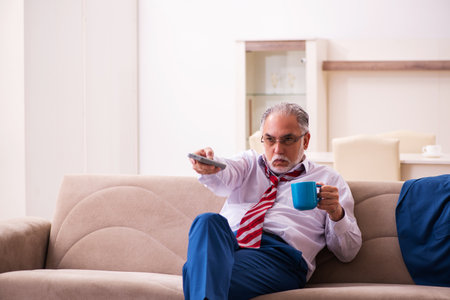 Old male boss employee watching tv at homeの写真素材