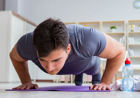 Young man exercising at home in sports and healthy lifestyle con