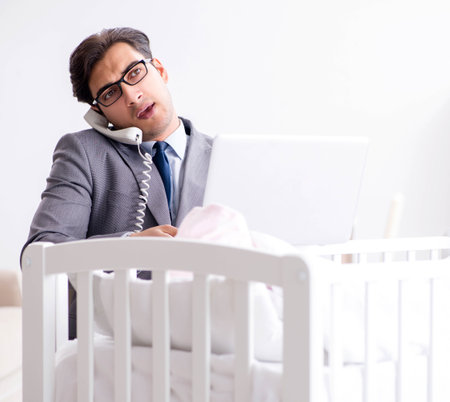 Young businessman trying to work from home caring after newbornの写真素材