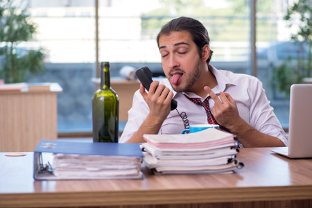 Young male alcohol addicted employee working in the officeの写真素材