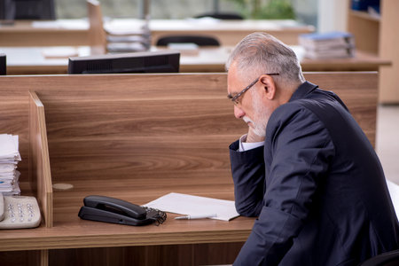 Old male employee sitting in the officeの写真素材