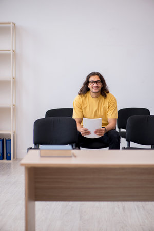 Young male student waiting for teacher in the classroomの写真素材