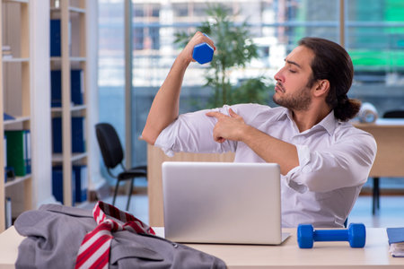 Young male employee doing sport exercises in the officeの写真素材