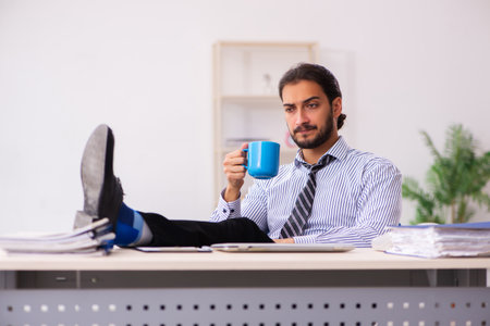 Young male employee drinking coffee during breakの写真素材