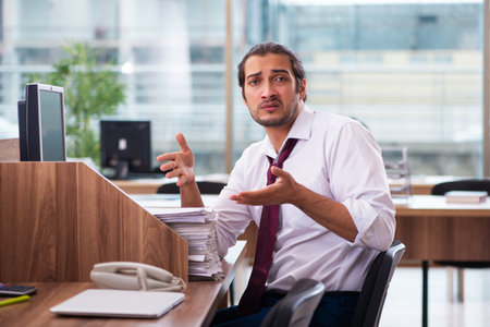 Young male employee and too many work in the officeの写真素材