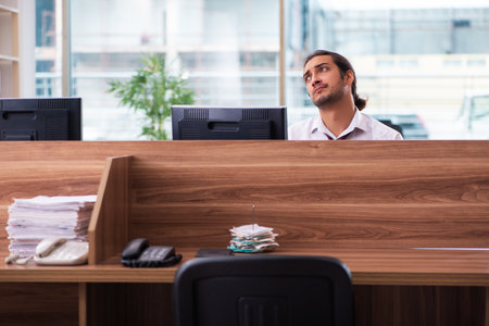 Young male employee and too many work in the officeの写真素材