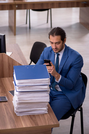 Young male employee unhappy with excessive work in the officeの写真素材