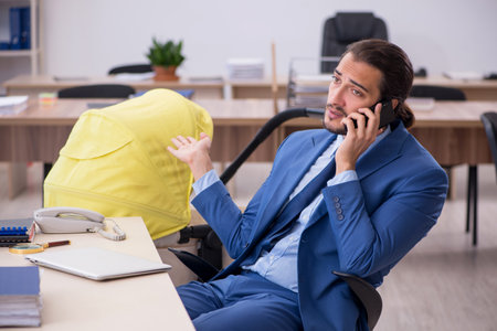 Young male employee looking after new born at workplaceの写真素材
