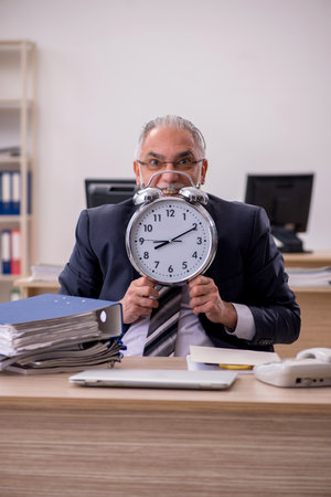 Aged businessman employee in time management conceptの写真素材